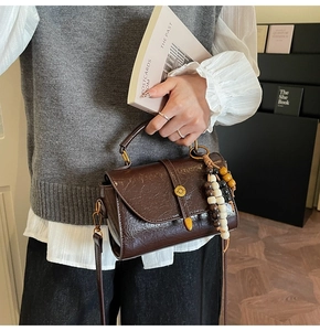 Detail of dark brown retro leather crossbody bag with colorful wooden bead charm