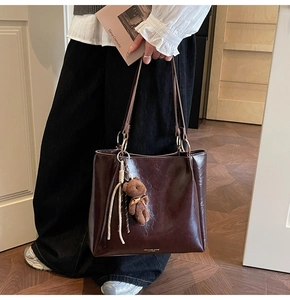 Détails du cabas en cuir marron foncé avec anneaux en métal et breloque ours en peluche