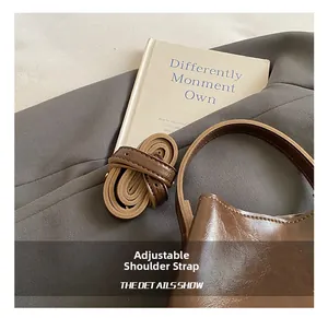 Détail montrant la bandoulière en cuir réglable et la finition de ce sac seau marron