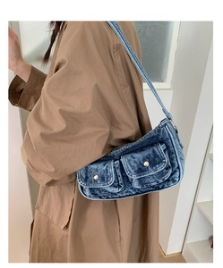 Detail of vintage blue washed denim shoulder bag with metal buckles on model