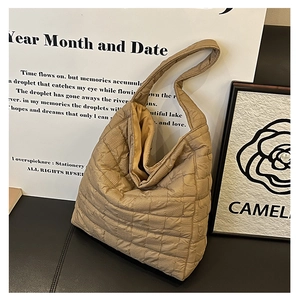 Macro shot of beige quilted puffer tote bag detail with soft padded shoulder strap texture