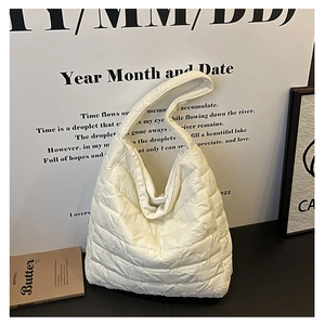 Detailed view of white quilted padded tote bag with soft puffer texture and square stitching
