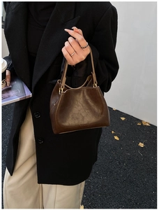 Gros plan du sac seau en cuir marron foncé présentant une texture fine et le logo HOCONU