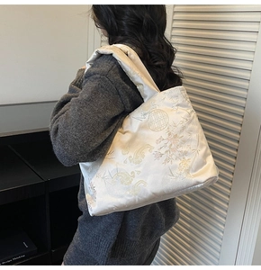Detail of white embroidered quilted tote bag with traditional Chinese cloud and floral patterns