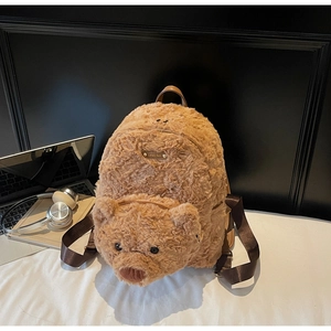 Détail d'un sac à dos ours en peluche avec bretelles réglables sur un bureau