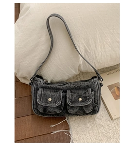 Detail of vintage washed black denim shoulder bag with metal zip and utility front pockets