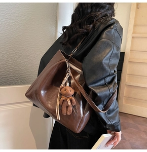 Détail d'un grand sac cabas en cuir marron avec un charm ours en décor de style de vie