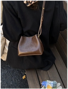Détail du sac seau en cuir marron foncé avec logo HOCOMU gaufré et coutures nettes
