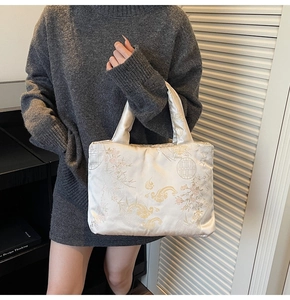 Close-up of white satin handbag with floral embroidery and Chinese traditional patterns