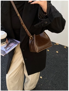 Détail du sac seau en cuir marron foncé avec sangle et boucle dorée