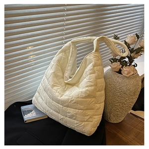 Close-up of quilted cream tote bag texture and wide strap with natural lighting