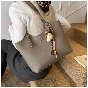 Detail view of large grey tote bag with lychee texture and plush bear charm decoration