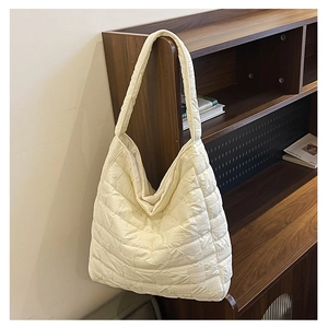 Close-up of cream white quilted tote bag hanging on a shelf in a cozy room setting