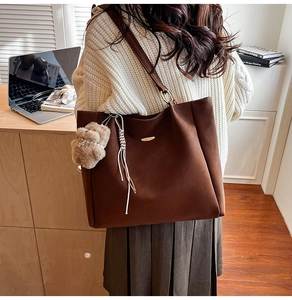 Detailed view of coffee brown suede tote bag with fringe and bear charm accessory