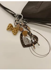 Détail du bijou de sac miroir cœur avec nœud léopard sur un sac à main marron