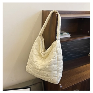 Detail of white quilted tote bag texture showing puffy nylon material and lattice stitching