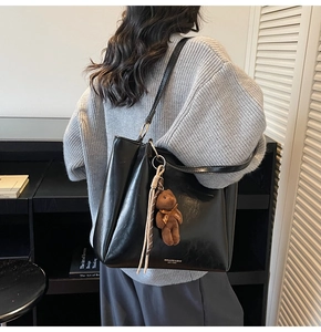 Détail d'un grand sac fourre-tout noir rétro en PU avec charmant pendentif d'ours