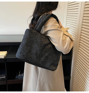 Detail of black pleated shoulder bag with unique quilted texture and spacious handle
