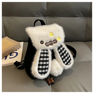 Detail of plush rabbit backpack with checkered ears and yellow flower on grey sofa