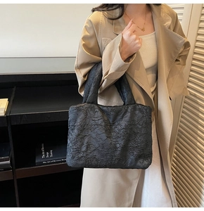 Detailed view of black crinkled texture fabric on a stylish minimalist handheld bag