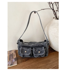 Close-up of retro gray washed denim shoulder bag with metal snap pockets on wood