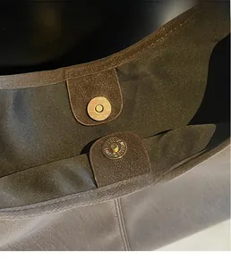 Detail of premium golden magnetic clasp with fine engraving on grey leather tote bag