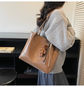 Détail du grand sac cabas en similicuir marron avec anneaux dorés et breloque peluche ours