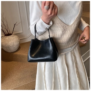 Détail du sac seau en cuir noir avec logo NOGONU embossé porté par un mannequin