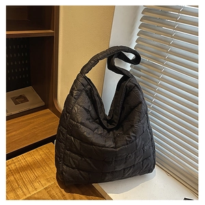 Detail of black quilted puffer tote bag featuring textured stitching and wide shoulder strap