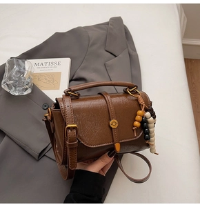 Detail of vintage brown crossbody bag with wooden beads and golden metallic lock