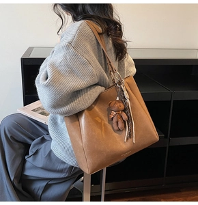 Détail d'un grand sac cabas marron avec charme ours en peluche et pompon