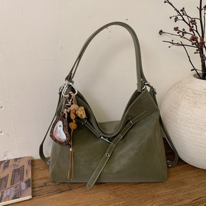 Sac fourre-tout vert olive en daim avec miroir cœur sur un bureau en bois rustique