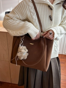 Brown large capacity tote bag with bear charm shown from a stylish side view angle
