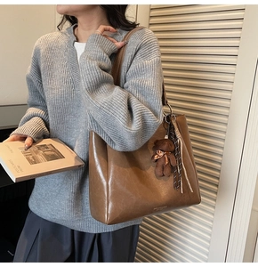 Sac fourre-tout vintage marron avec charm ours et gland sur l'épaule du modèle