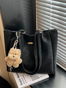 Black PU leather tote bag with gold rings and cute dog charm shown in a lifestyle setting