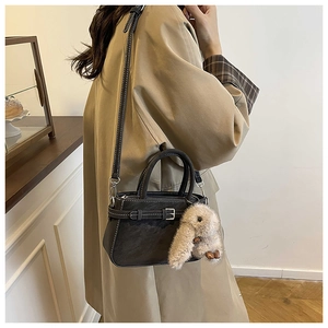 Dettaglio mini borsa in pelle nera opaca con cuciture a contrasto e ciondolo a coniglio