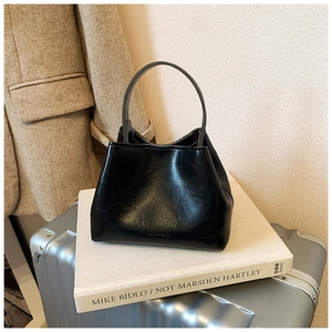 Détail du sac seau noir avec poignée ronde et logo de marque embossé sur le cuir
