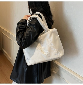 Elegant floral embroidery detail on cream shoulder bag with silky jacquard texture