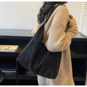 Macro shot of matte black suede texture and wide strap of the retro oversized hobo bag