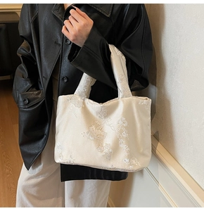 Close-up of white floral embroidery on a cream satin Chinese style tote handbag