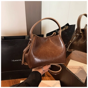 Détail du sac seau vintage en cuir marron montrant sa texture et son éclat poli