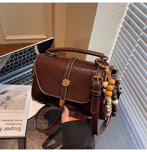 Detail of dark brown vintage satchel with glossy wrinkled texture and wooden beads