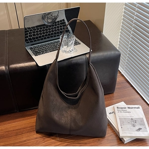 Detail of a large dark brown suede tote bag with a matte texture on a leather bench