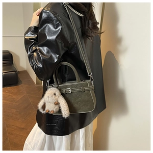 Dark green matte bag with leather strap buckle, plush rabbit charm, and dual straps
