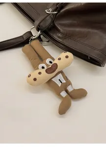 Close-up of a brown plush cartoon charm with polka dots hanging on a leather tote bag