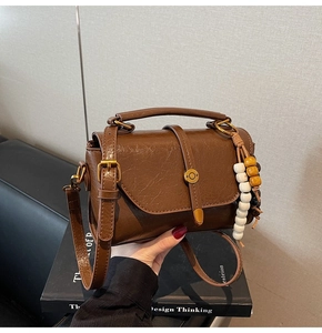 Close-up of brown textured crossbody bag with vintage beads and brass hardware