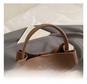 Close-up of litchi grain dark brown leather handbag handle and silver hardware detail