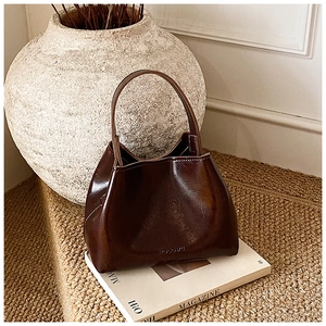 Détail du sac seau en cuir ciré marron rouge foncé avec logo HOCOMU en relief