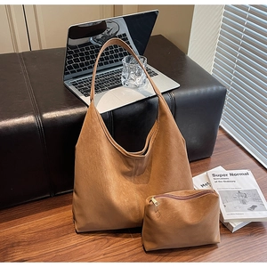 Detail of vintage matte brown tote bag with matching inner pouch set on a wooden floor