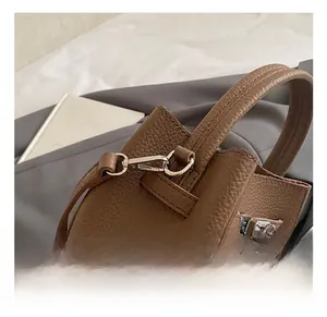 Detail of lychee pattern brown leather handle with premium silver metal buckle on bag
